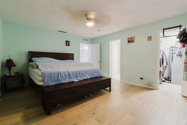 bedroom featuring ceiling fan, light hardwood / wood-style flooring, and a textured ceiling