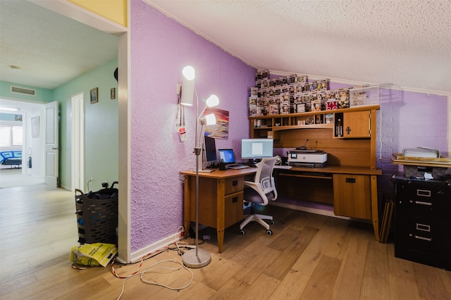 office area featuring a textured ceiling, light hardwood / wood-style flooring, and vaulted ceiling