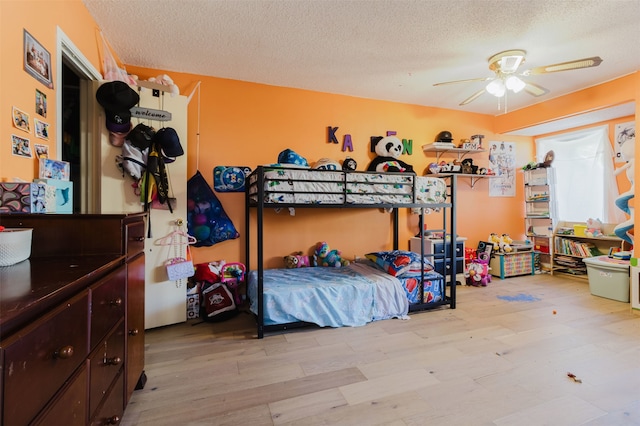 bedroom featuring ceiling fan, light hardwood / wood-style floors, and a textured ceiling