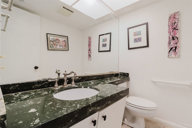 bathroom with vanity, toilet, and a skylight