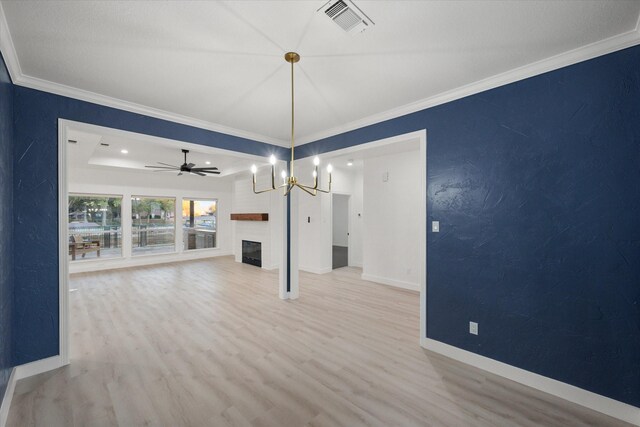 unfurnished dining area with crown molding, a fireplace, light hardwood / wood-style floors, and ceiling fan with notable chandelier