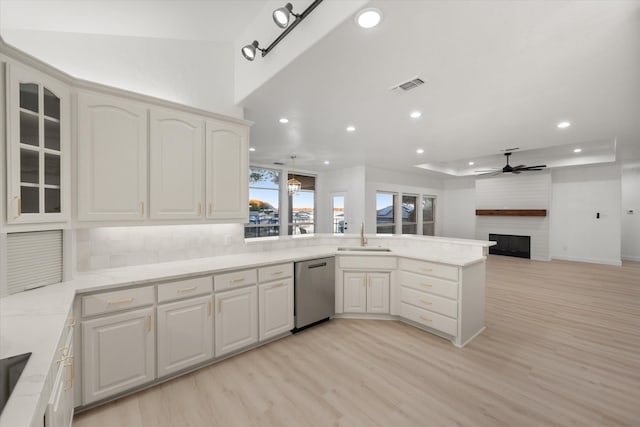 kitchen featuring kitchen peninsula, a large fireplace, sink, light hardwood / wood-style flooring, and dishwasher