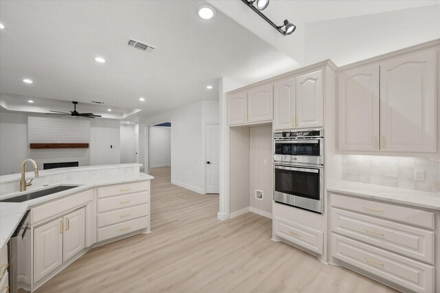 kitchen with stainless steel appliances, white cabinetry, ceiling fan, and sink