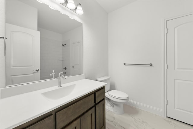 bathroom with a tile shower, vanity, and toilet