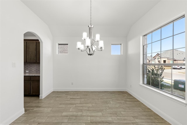 unfurnished dining area featuring vaulted ceiling and an inviting chandelier