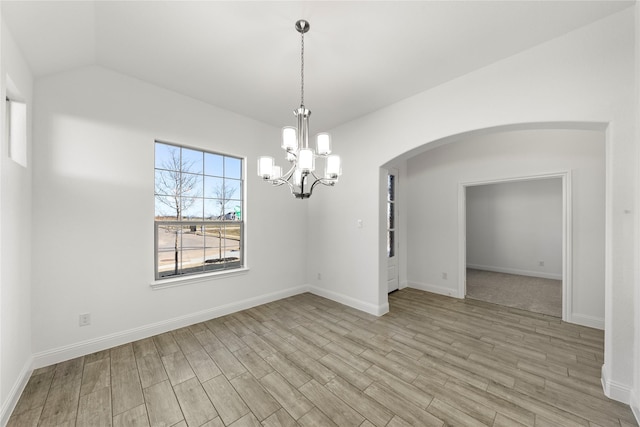 unfurnished dining area featuring a chandelier, lofted ceiling, and light hardwood / wood-style flooring