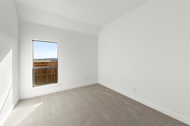 carpeted spare room with lofted ceiling