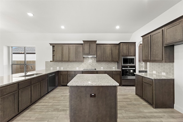 kitchen with stainless steel appliances, dark brown cabinets, sink, and light stone counters