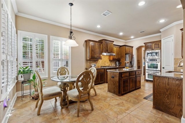 kitchen with tasteful backsplash, light stone countertops, a center island, and appliances with stainless steel finishes