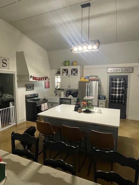 kitchen featuring sink, pendant lighting, a kitchen bar, white cabinets, and appliances with stainless steel finishes