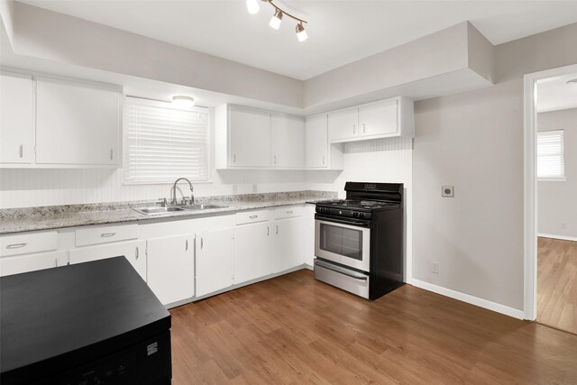 kitchen featuring light stone counters, gas range, sink, hardwood / wood-style flooring, and white cabinetry