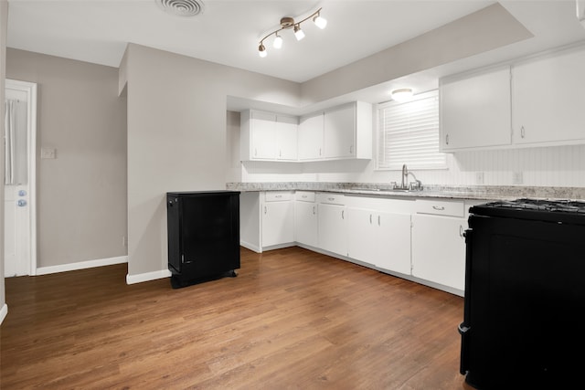 kitchen with black stove, light wood-type flooring, white cabinetry, and sink