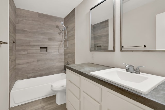 full bathroom with hardwood / wood-style floors, vanity, toilet, and tiled shower / bath combo