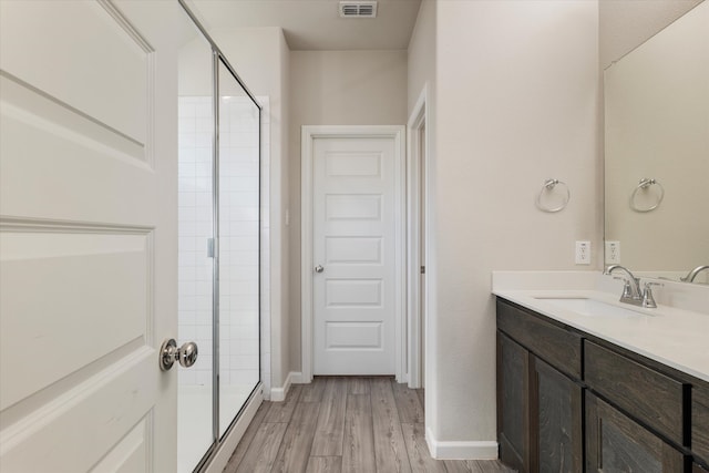 bathroom featuring hardwood / wood-style flooring, vanity, and a shower with door