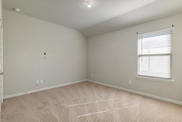 carpeted spare room featuring lofted ceiling