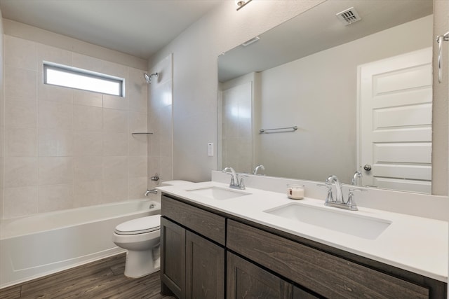 full bathroom featuring vanity, hardwood / wood-style floors, tiled shower / bath combo, and toilet