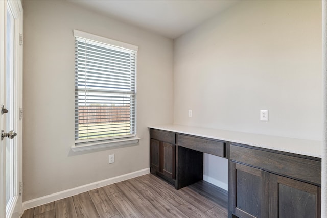 unfurnished office featuring light hardwood / wood-style flooring and built in desk