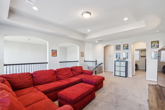 carpeted living room featuring a tray ceiling