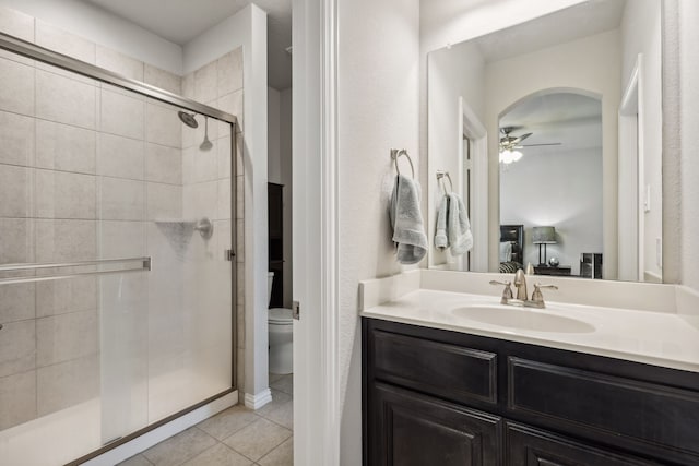 bathroom featuring ceiling fan, walk in shower, tile patterned flooring, toilet, and vanity