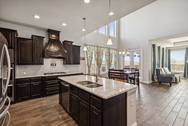 kitchen featuring dark hardwood / wood-style floors, a center island with sink, decorative light fixtures, and custom range hood