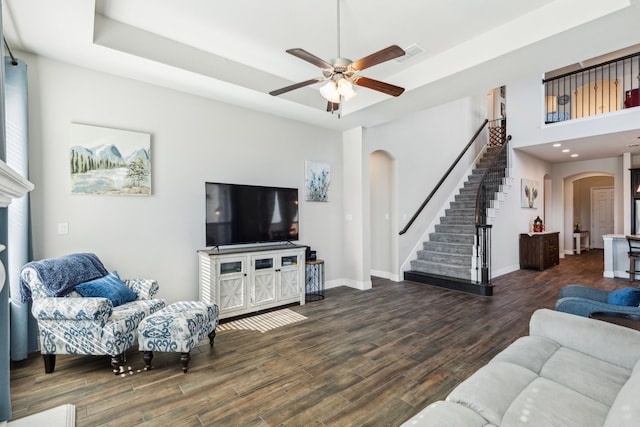 living room featuring ceiling fan, dark hardwood / wood-style flooring, and a towering ceiling