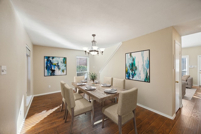 dining space with dark hardwood / wood-style flooring and an inviting chandelier