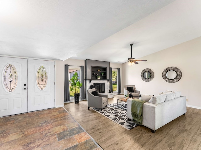 living room with ceiling fan, wood-type flooring, and a fireplace