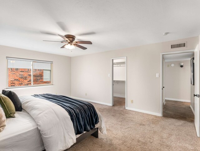 carpeted bedroom with ceiling fan, a walk in closet, and a closet