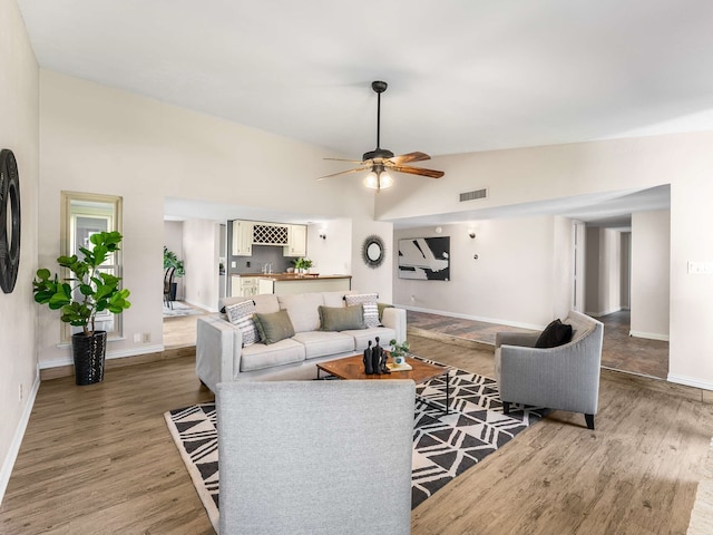 living room with wood-type flooring, vaulted ceiling, and ceiling fan