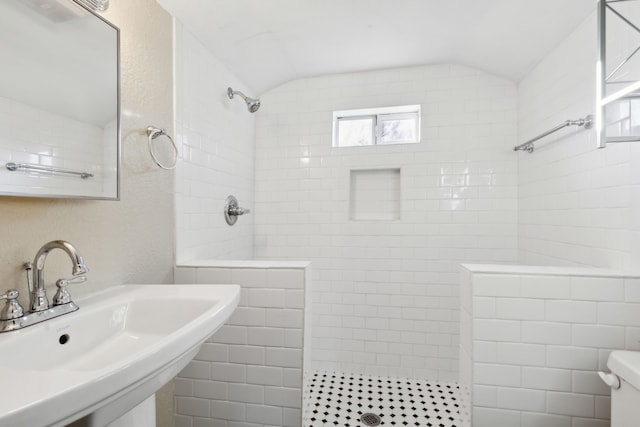 bathroom featuring tiled shower, vaulted ceiling, toilet, and sink