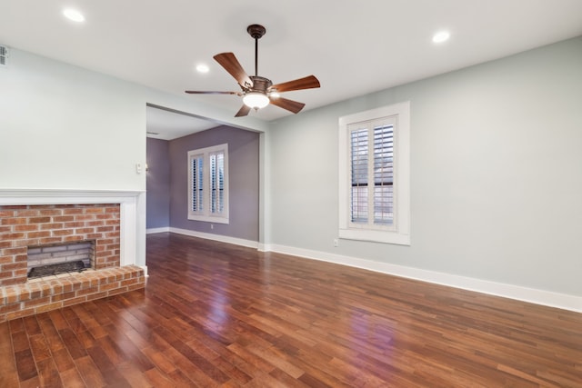 unfurnished living room featuring a brick fireplace, ceiling fan, and dark wood-type flooring