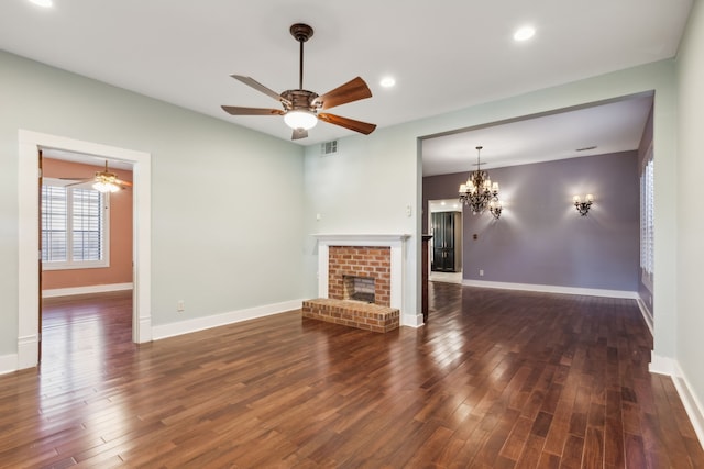 unfurnished living room with a fireplace, ceiling fan with notable chandelier, and dark hardwood / wood-style floors