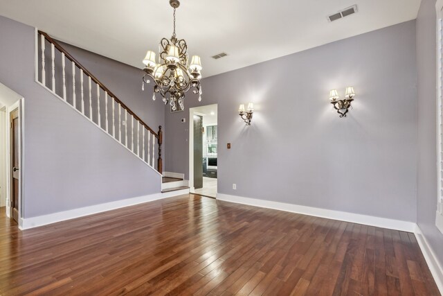 unfurnished living room featuring dark hardwood / wood-style floors and an inviting chandelier