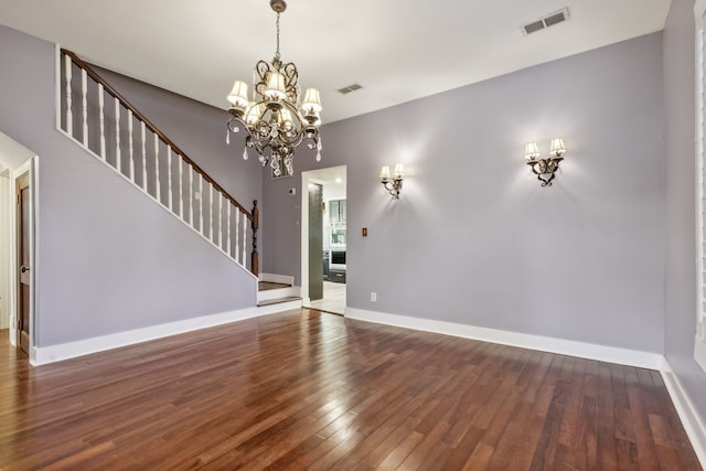 unfurnished living room with an inviting chandelier and dark hardwood / wood-style floors