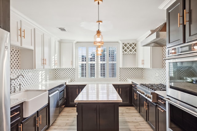 kitchen with a center island, sink, light hardwood / wood-style flooring, decorative backsplash, and stainless steel appliances