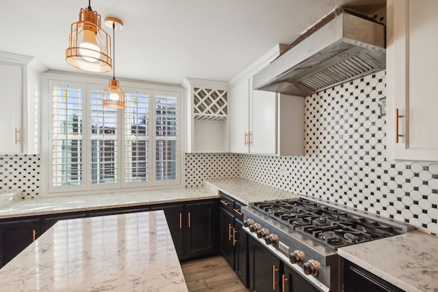 kitchen with pendant lighting, stainless steel stovetop, white cabinets, wall chimney range hood, and decorative backsplash