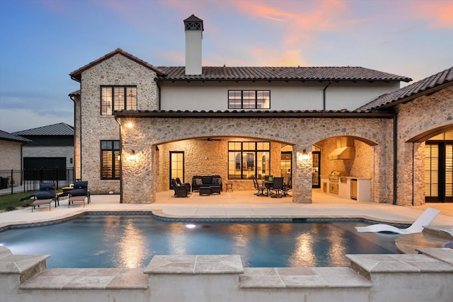 pool at dusk with a patio area, an outdoor hangout area, and area for grilling