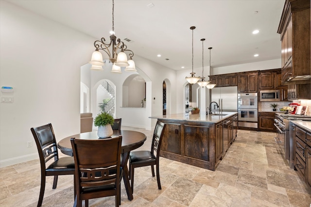 kitchen with pendant lighting, premium range hood, decorative backsplash, a notable chandelier, and double oven range