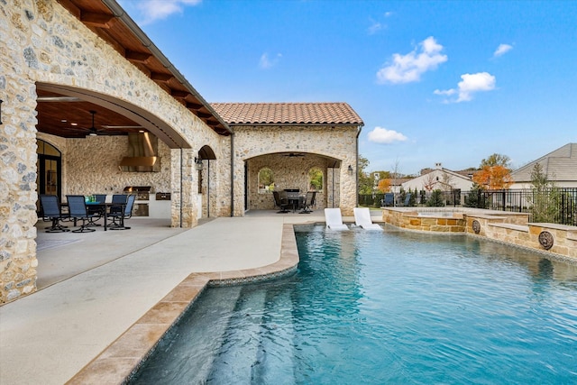 view of pool featuring exterior kitchen, a patio, and ceiling fan