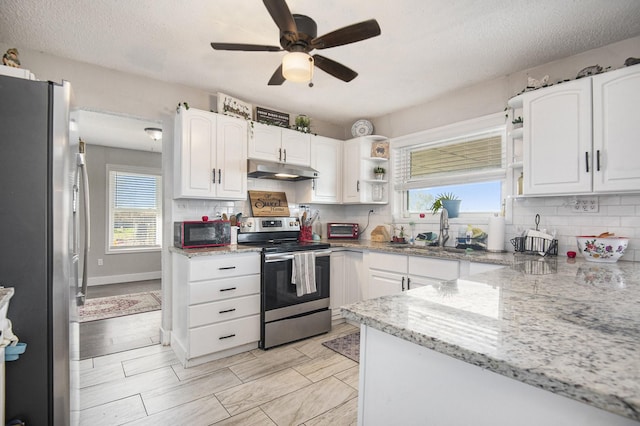 kitchen with backsplash, light stone countertops, white cabinets, and appliances with stainless steel finishes