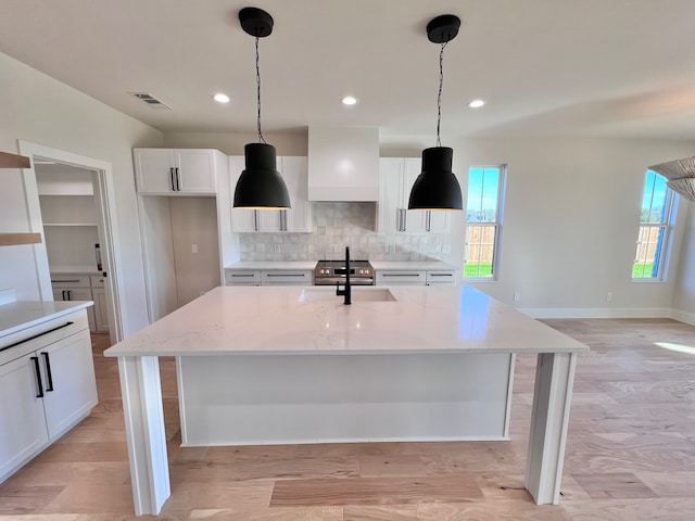 kitchen with white cabinets, light stone counters, plenty of natural light, and sink