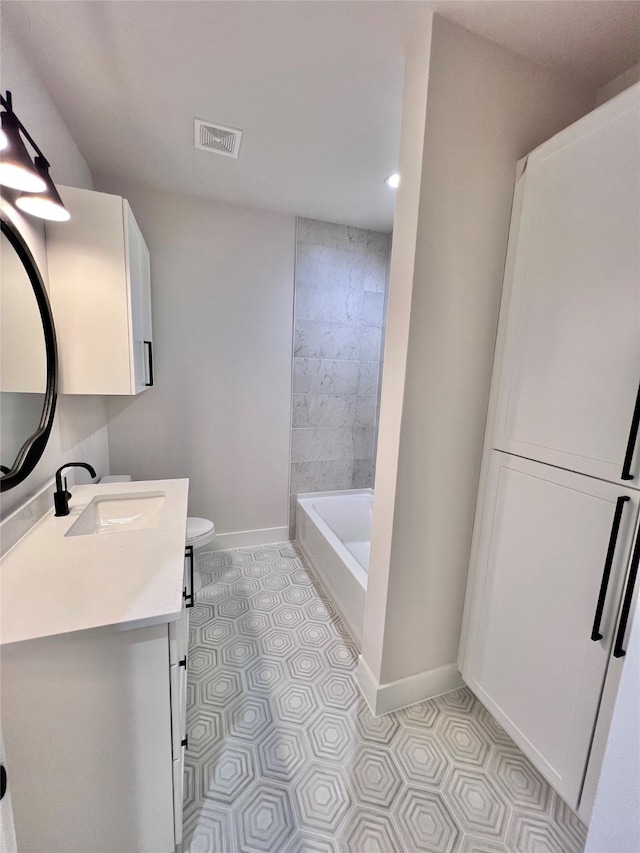 bathroom with a bathing tub, vanity, toilet, and tile patterned floors