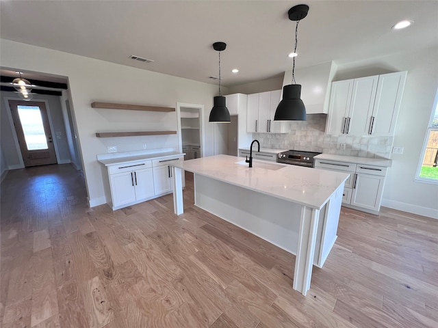 kitchen featuring a wealth of natural light, light hardwood / wood-style flooring, white cabinets, and light stone countertops