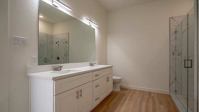 bathroom with wood-type flooring, vanity, toilet, and a shower with door