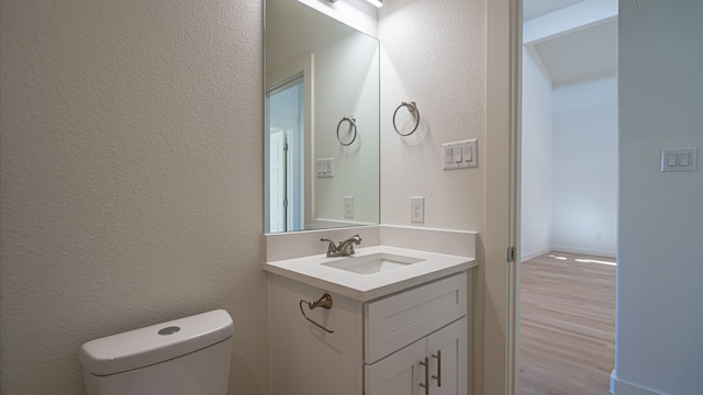 bathroom with toilet, vanity, and hardwood / wood-style flooring