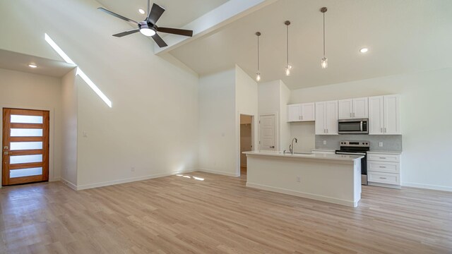 kitchen with white cabinetry, hanging light fixtures, an island with sink, light hardwood / wood-style floors, and appliances with stainless steel finishes