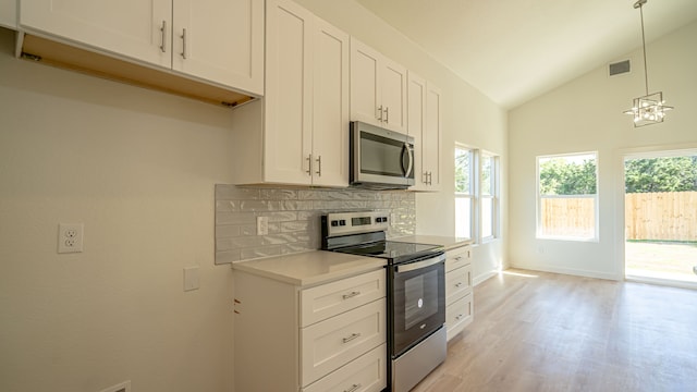 kitchen with white cabinets, decorative light fixtures, stainless steel appliances, and light hardwood / wood-style flooring