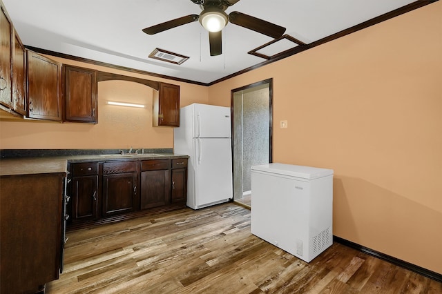 kitchen featuring refrigerator, white refrigerator, light hardwood / wood-style flooring, and crown molding