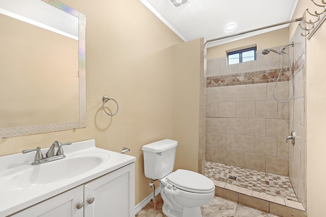 bathroom with tiled shower, vanity, toilet, and ornamental molding