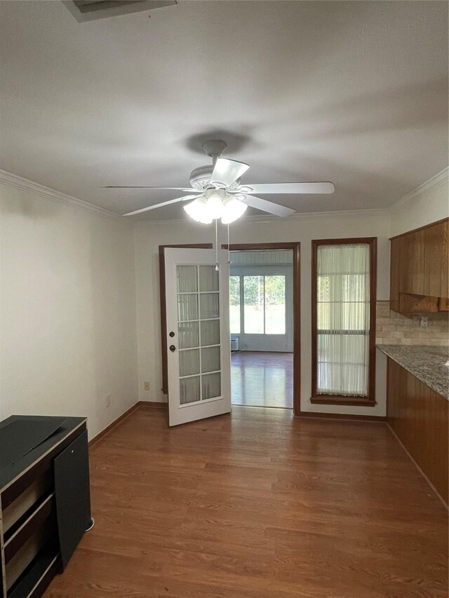 interior space featuring ceiling fan, ornamental molding, wood finished floors, and baseboards